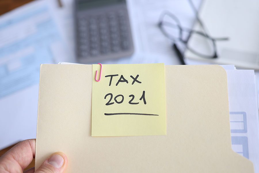 An accountant and tax expert in Springfield, IL holding a standard file that has a tax 2021 sticky note and paper clip attached.