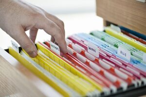 A person looking through a color-coded file system at a tax and bookkeeping firm in Springfield, IL.
