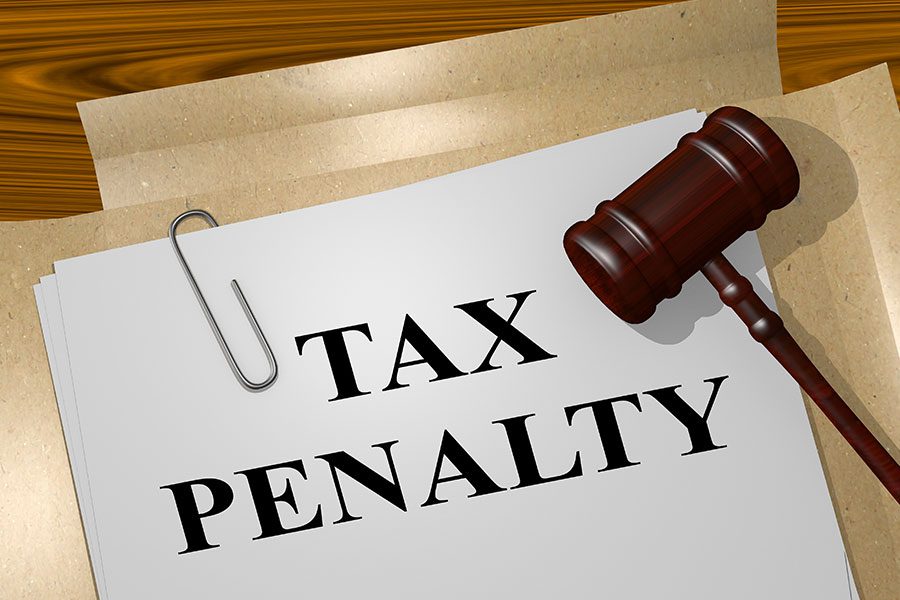 The words tax penalty written on a white sheet of paper with a court gavel lying next to it on a desk in Springfield, IL.