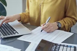 JLW Tax & Bookkeeping Services—A businesswoman uses sheets and a laptop to accurately keep the books for her small business in Springfield, IL