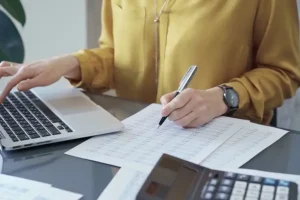JLW Tax & Bookkeeping Services—A businesswoman uses sheets and a laptop to accurately keep the books for her small business in Springfield, IL