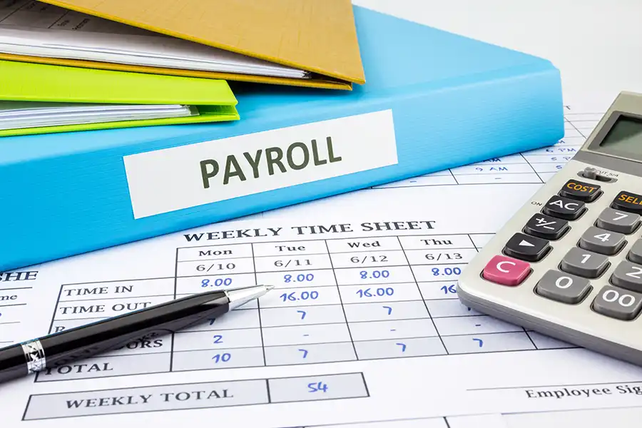 JLW Tax & Bookkeeping Services—A calculator, papers, and a binder labeled payroll on an office desk in Springfield, IL.
