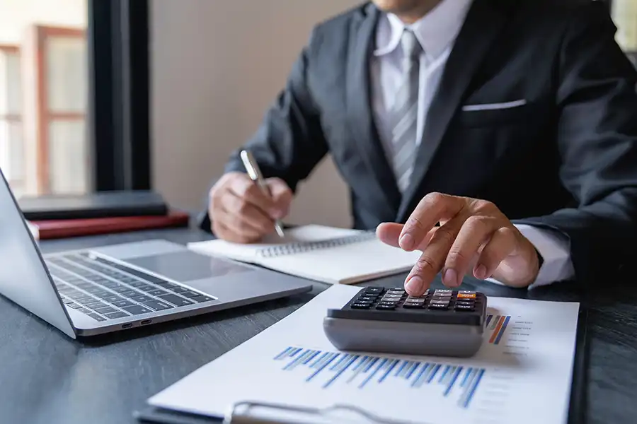 JLW Tax & Bookkeeping Services—A professional tax consultant in Springfield, IL, uses a calculator and computer to check a business’s records and perform a monthly reconciliation.